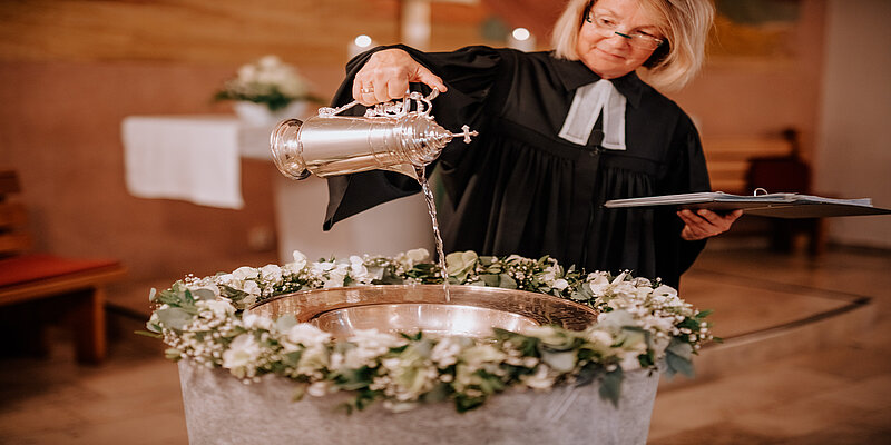 Foto: Pfarrerin Gaby Bach gießt Taufwasser ein